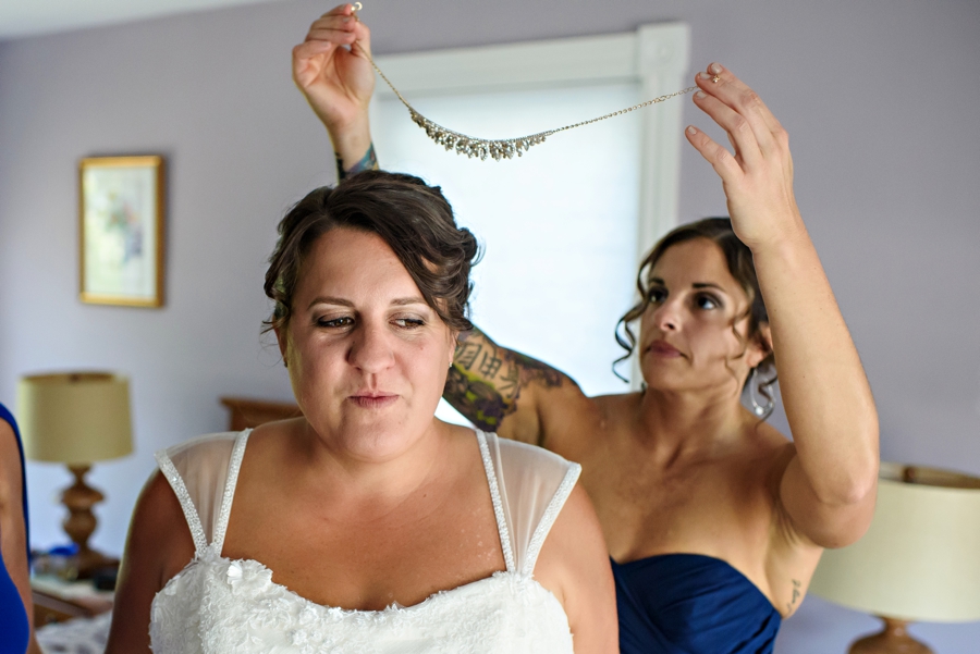 A maid of honor putting jewelry on the bride during the getting ready on her wedding day.